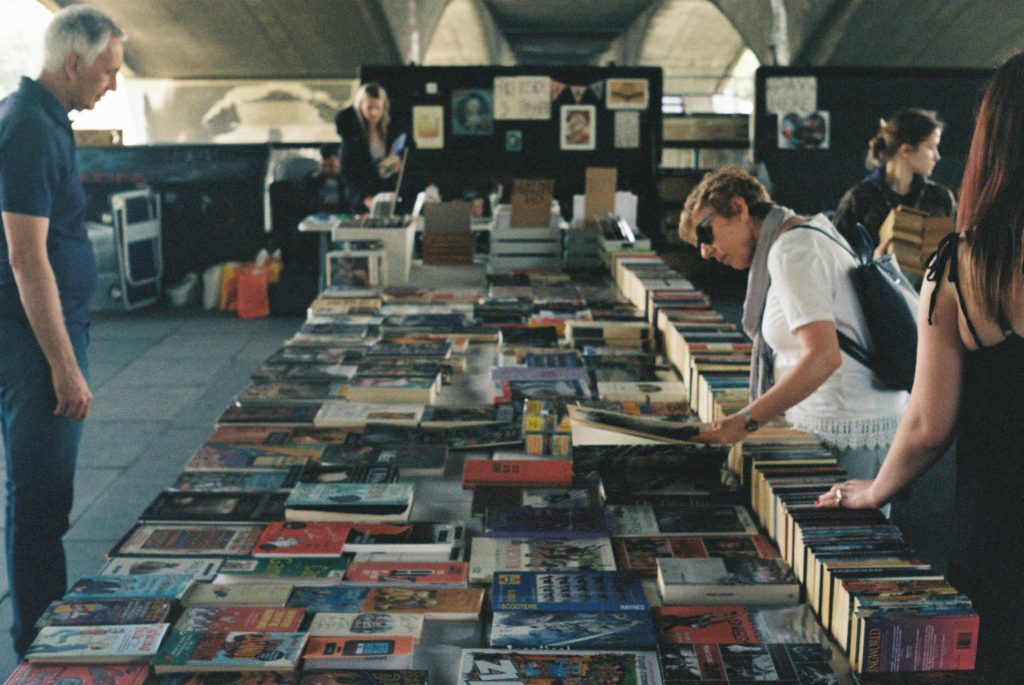 Picture of people looking at some books displayed on a table.