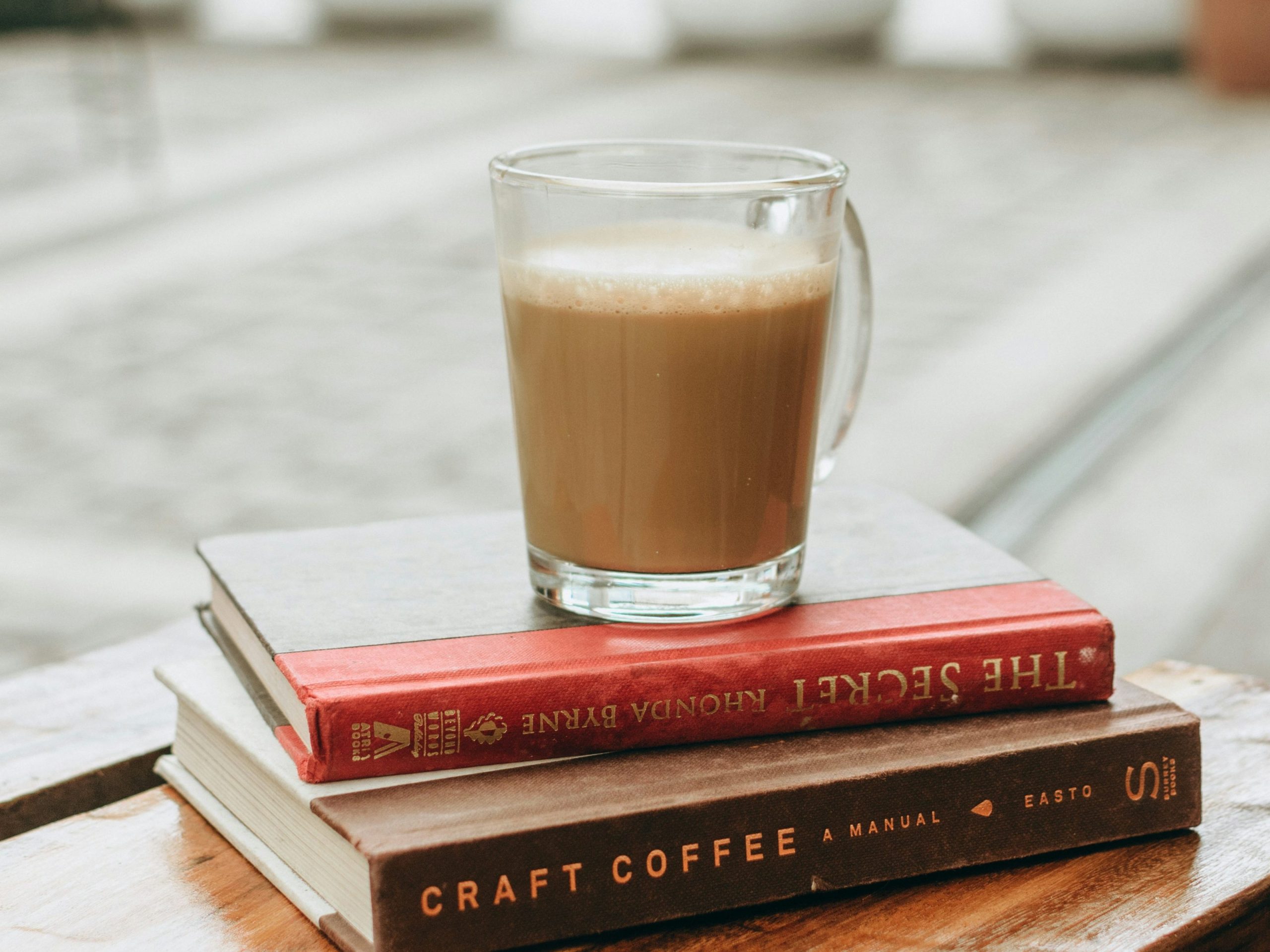 A picture of a cup of coffee standing on top of two books. One of the books is about coffee.